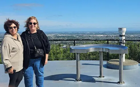 Two people standing at a scenic viewpoint overlooking Christchurch city on a half-day tour.