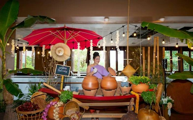 Woman preparing Thai curry at Siam Niramit Phuket show, surrounded by traditional decor.