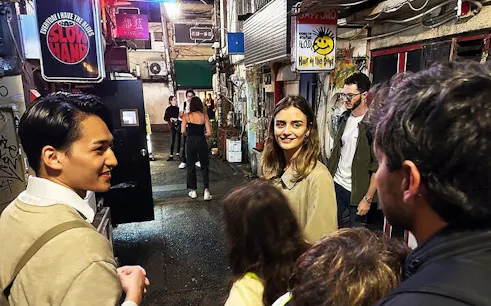 Shinjuku alley with tourists exploring nightlife and hidden bars in Tokyo.