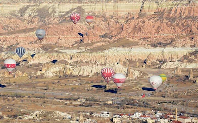 Hot air balloons floating over Cappadocia's unique rock formations at sunrise.