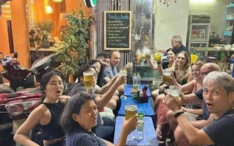Group enjoying drinks at a local eatery during Hanoi E-Scooter City Tour.