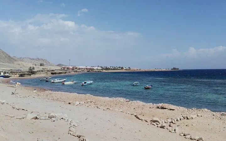 Boats along the shore at 3 Pools National Park, Dahab, with clear blue water.