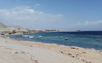 Boats along the shore at 3 Pools National Park, Dahab, with clear blue water.