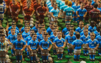 Miniature soccer player figurines in blue jerseys at Naples Crib Street market.