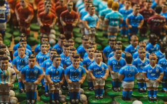 Miniature soccer player figurines in blue jerseys at Naples Crib Street market.