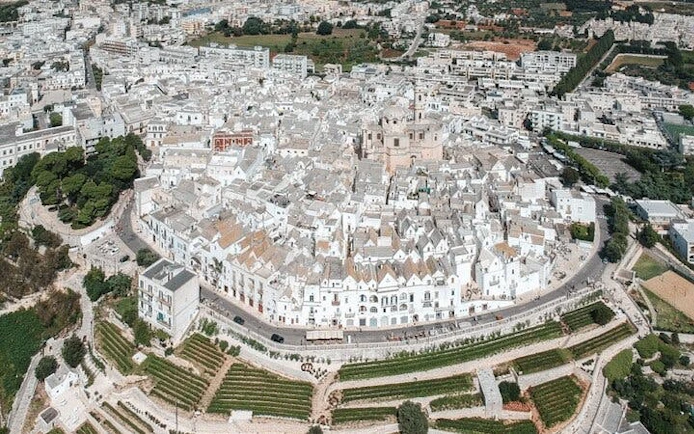 Aerial view of Locorotondo's circular old town with whitewashed buildings in Valle d'Itria, Italy.
