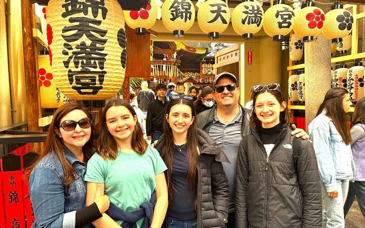 Group enjoying Nishiki Market tour in Kyoto, surrounded by traditional lanterns and bustling atmosphere.
