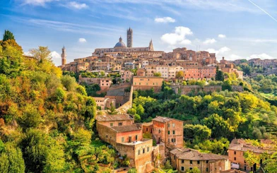 Siena cityscape with historic buildings and cathedral, view from a hill, Italy.