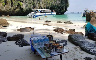 Speedboat anchored on Krabi beach with picnic setup for 4 Islands Sunset and Plankton tour.