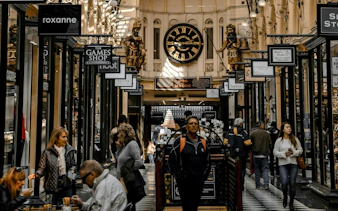 Melbourne's Royal Arcade with shoppers and historic clock on self-guided audio tour.