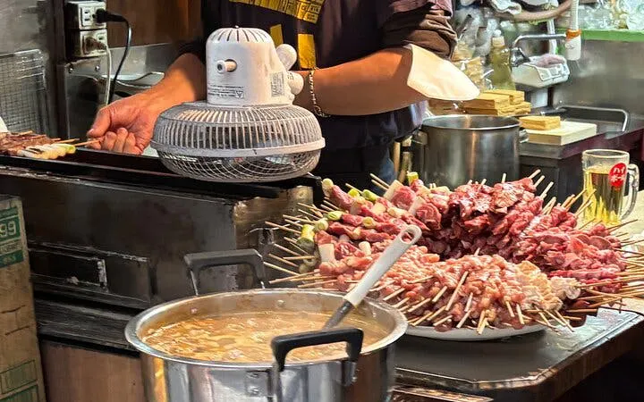 Street vendor grilling skewers in Shinjuku during Tokyo bar hopping tour.