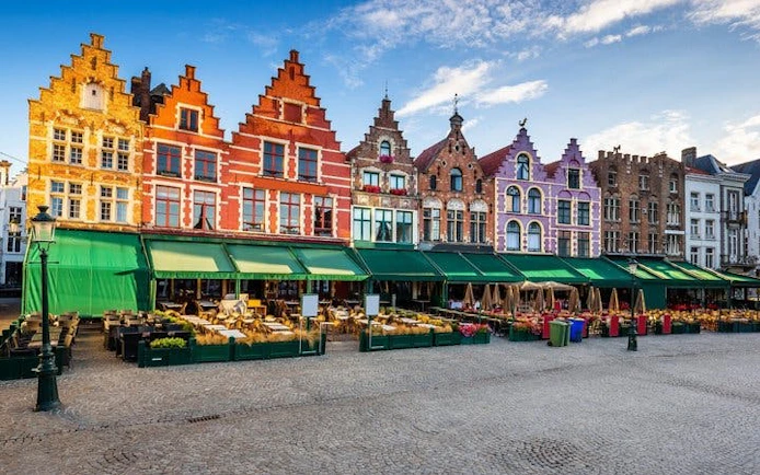 Colorful gabled buildings in Bruges market square, part of self-guided walking tour.