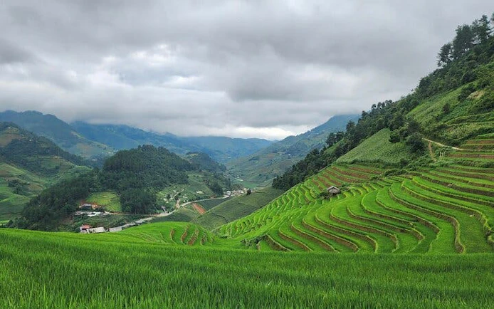 Terraced rice fields in Mu Cang Chai, Vietnam, with distant ethnic villages and lush landscapes.