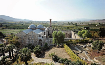 Ancient stone building in Ephesus surrounded by greenery, part of a 2-day tour from Istanbul.