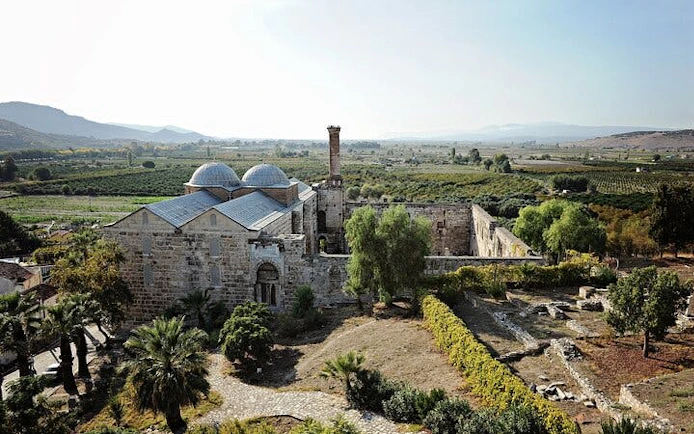 Ancient stone building in Ephesus surrounded by greenery, part of a 2-day tour from Istanbul.