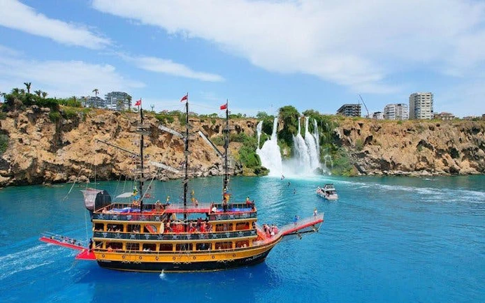 Pirate-themed boat near Lower Duden Waterfall in Antalya, with tourists on deck.