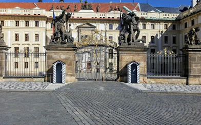 Prague Castle entrance with ornate gates and statues, part of Gothic city exploration game.
