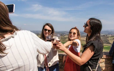 Group enjoying wine tasting with scenic Tuscan vineyard view on Pisa, Vinci, and Tuscan Winery tour.