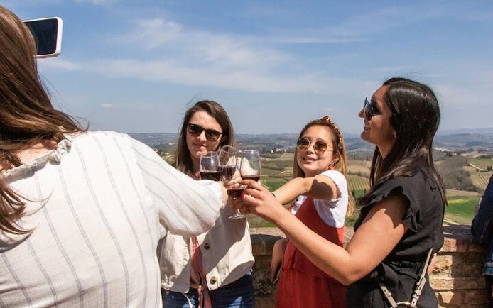 Group enjoying wine tasting with scenic Tuscan vineyard view on Pisa, Vinci, and Tuscan Winery tour.