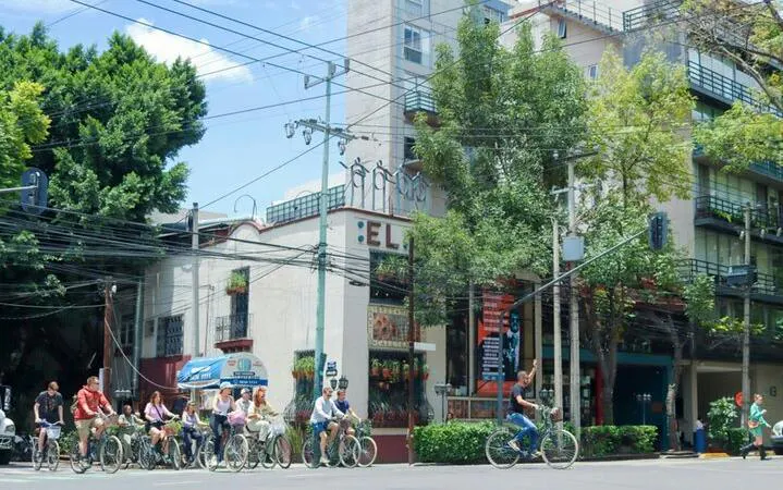 Cyclists on a taco tour in Mexico City, passing by a local restaurant.
