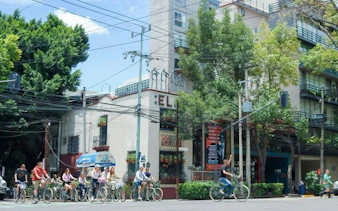 Cyclists on a taco tour in Mexico City, passing by a local restaurant.