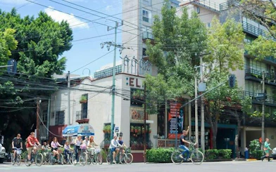 Cyclists on a taco tour in Mexico City, passing by a local restaurant.