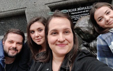 Group exploring haunted Liverpool statue during self-guided city game.
