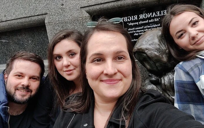 Group exploring haunted Liverpool statue during self-guided city game.