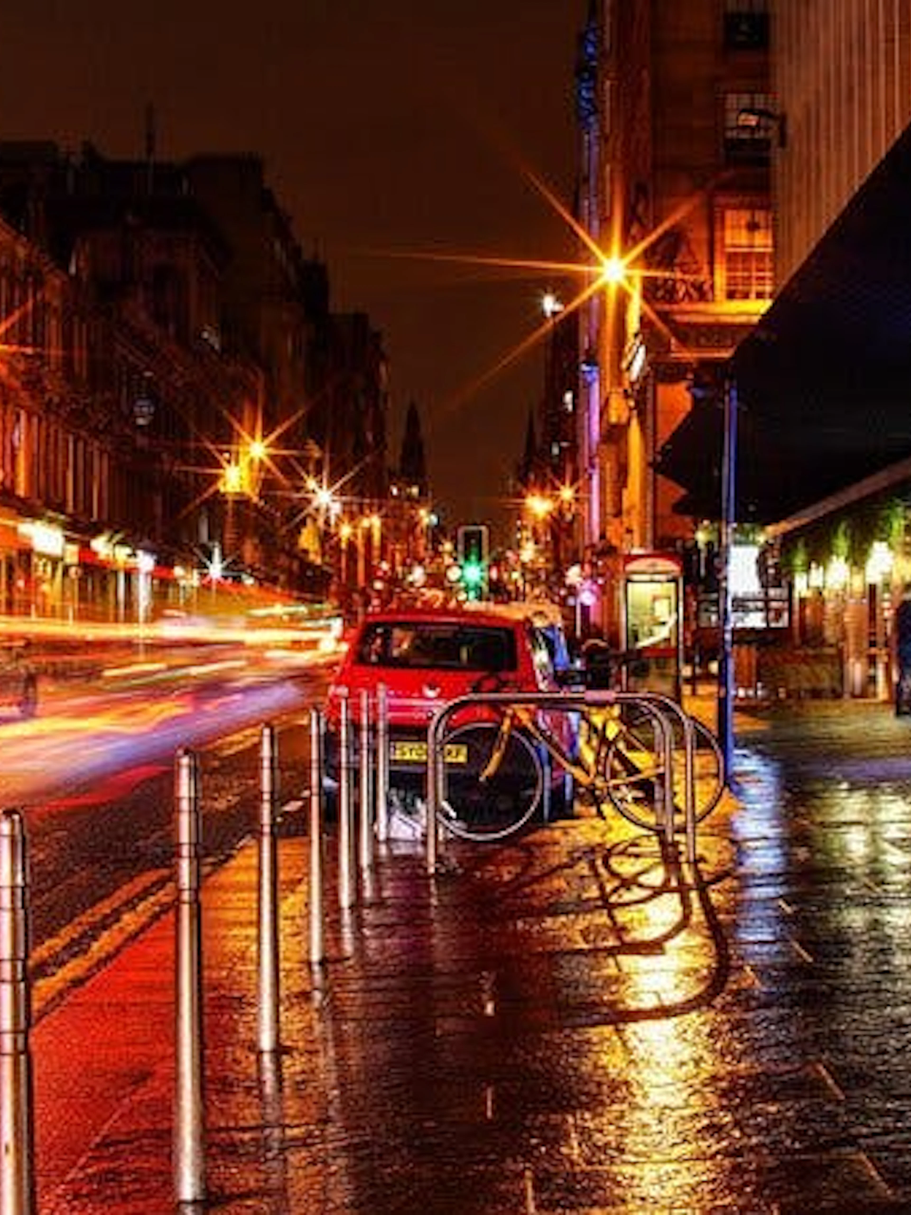 Nighttime street scene in Glasgow with blurred car lights, part of the Ghosts of Glasgow self-guided city exploration game.