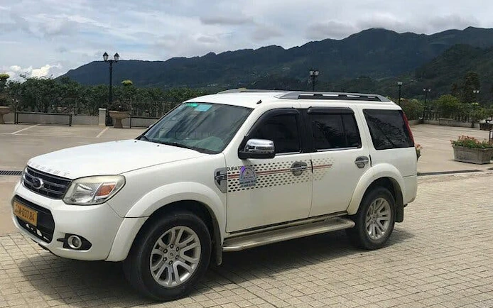 Private transfer vehicle for Sapa to Lào Cai Train Station with mountain backdrop.