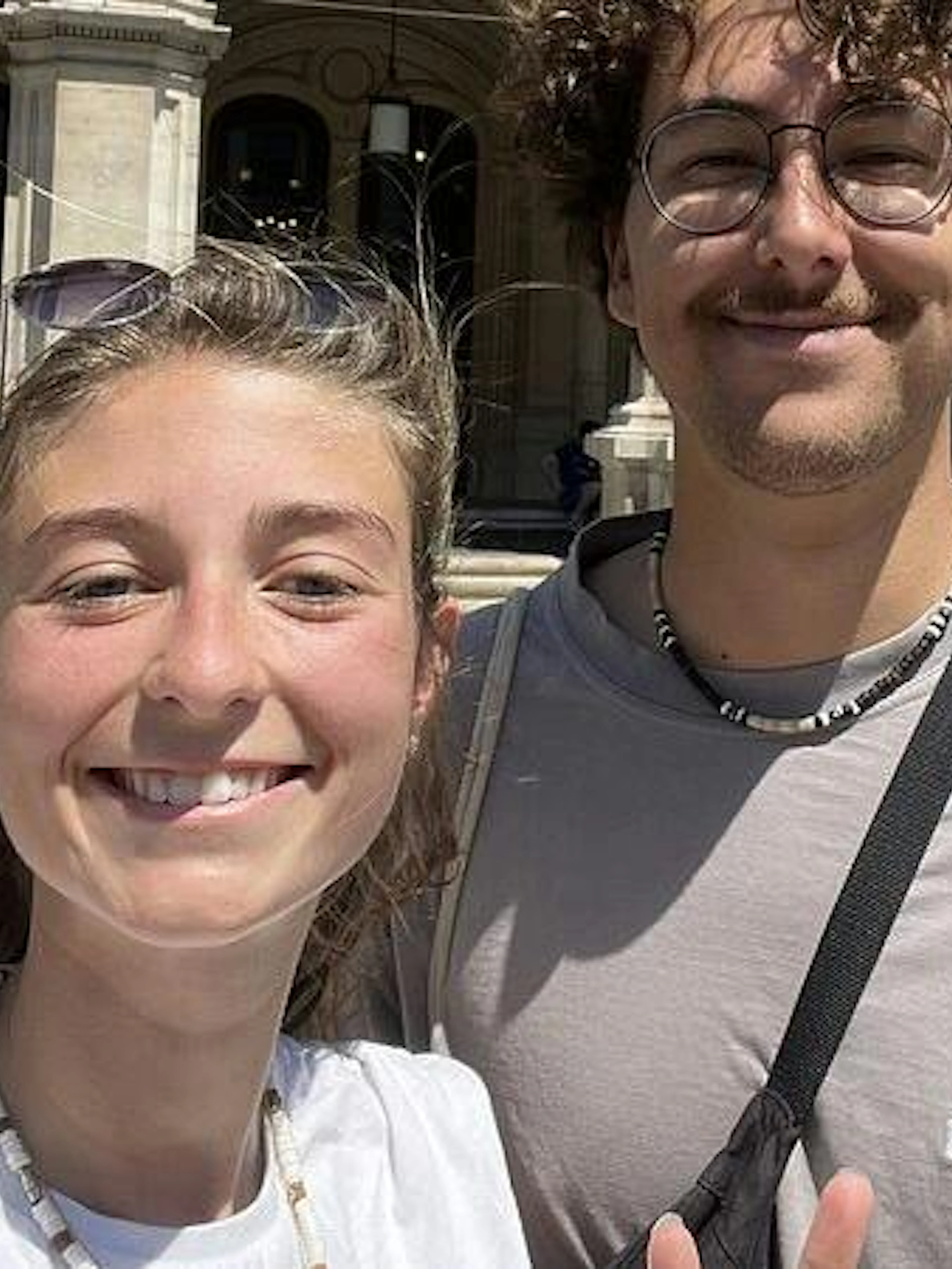 Two people smiling in front of a historic building in Vienna during a self-guided city exploration game.