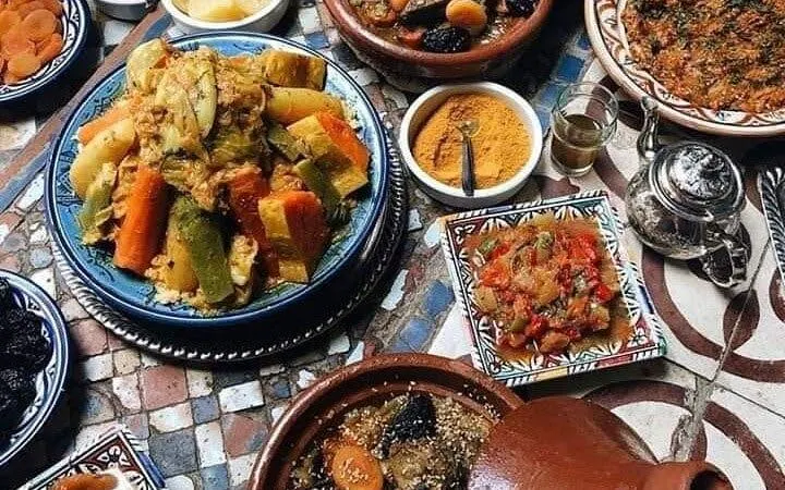 Moroccan dishes with vegetables and spices on a mosaic table during a cooking class in Marrakesh.