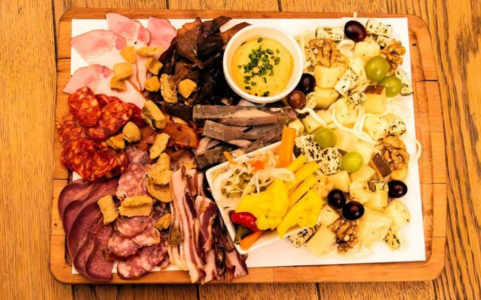 Slovak charcuterie board with meats, cheeses, and pickles on Bratislava food tour.
