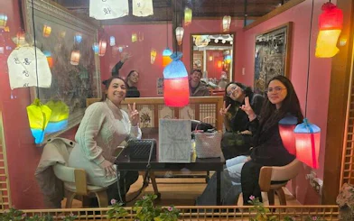 Group enjoying traditional Korean meal under colorful lanterns, Seoul Dongmyo Flea and Gwangjang Market Tour.