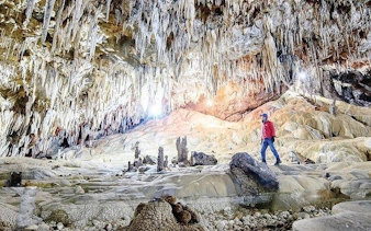 Person exploring Pusamcap Cave with stalactites in Sapa during motorbike tour.