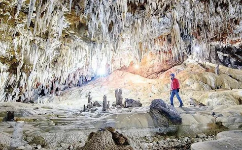 Person exploring Pusamcap Cave with stalactites in Sapa during motorbike tour.