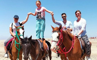 Horse riding group holding hands on horses in Hurghada desert near Red Sea.