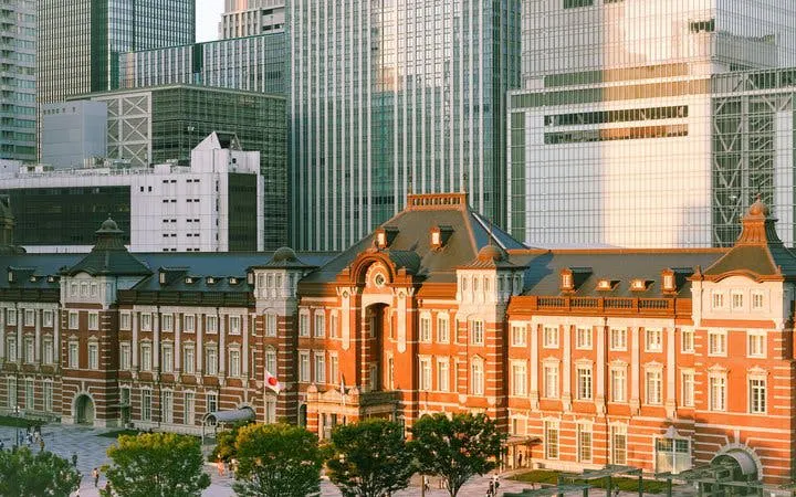 Tokyo Station historic facade with modern skyscrapers in the background.