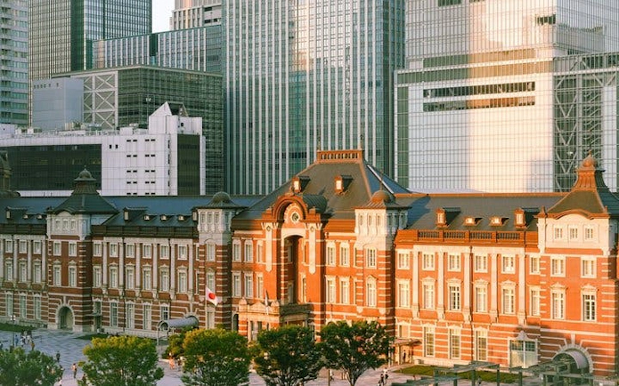 Tokyo Station historic facade with modern skyscrapers in the background.