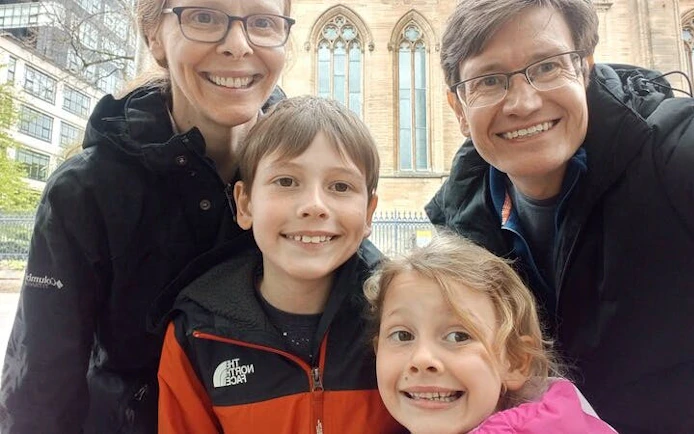 Family posing in front of a historic building in Glasgow during a self-guided city exploration game.