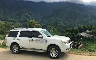 SUV for private transfer from Sapa to Lào Cai Train Station with mountain backdrop.