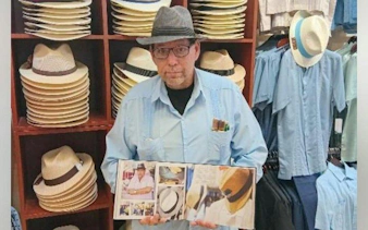 Man showcasing Cuban hats and cultural book in Little Havana, Miami shop.