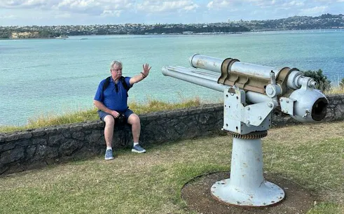 Man sitting near historic cannon overlooking Auckland harbor on private tour.