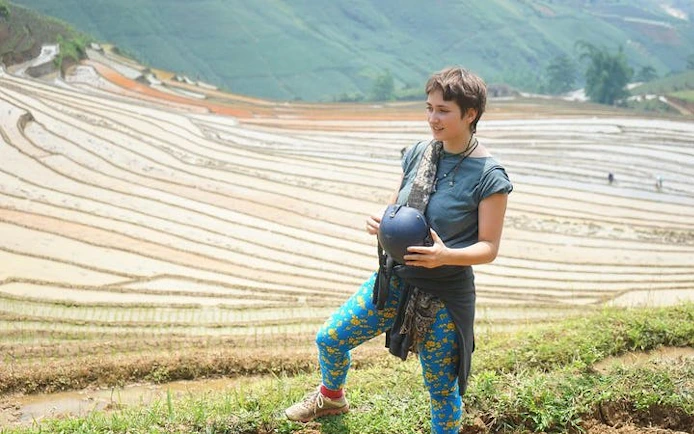Traveler standing by terraced rice fields in Sapa during motorbike tour.