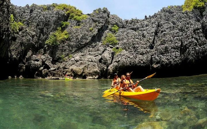 Kayakers paddling near rocky cliffs in Ang Thong National Marine Park, Koh Samui.