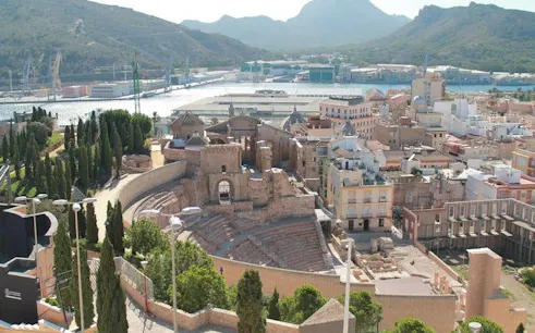 Roman Theatre ruins in Cartagena with cityscape and mountains in the background.