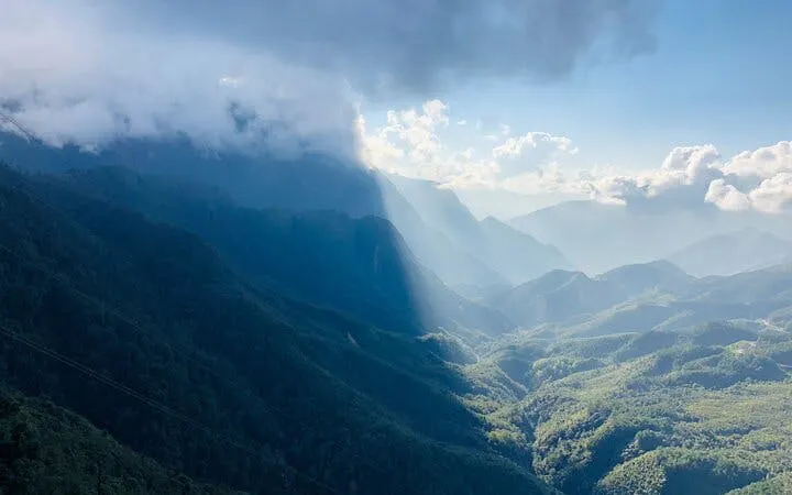 Sa Pa mountain view with misty peaks and sunlight, part of motorbike tour to Silver Waterfall.