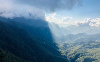 Sa Pa mountain view with misty peaks and sunlight, part of motorbike tour to Silver Waterfall.