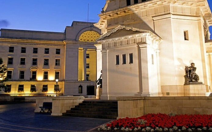 Birmingham city square at dusk with historic architecture and statues.