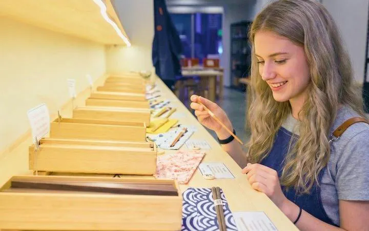 Chopstick-making workshop participant engraving kanji in Osaka Namba.